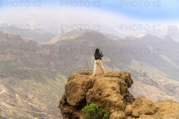 Woman photographing a scenic mountain range in gran canaria, canary islands, enjoying freedom and