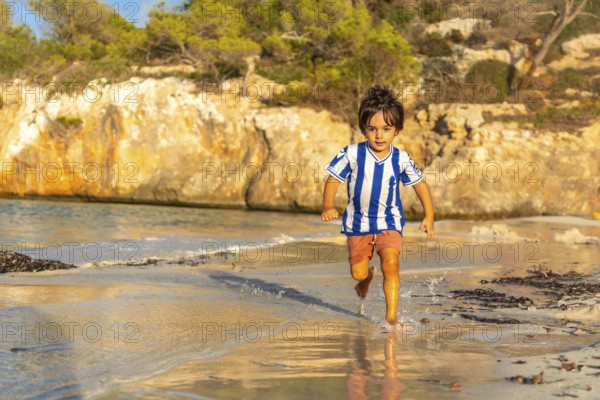 Carefree child enjoying summer holidays, running along the shore of s'amarador beach in mallorca,