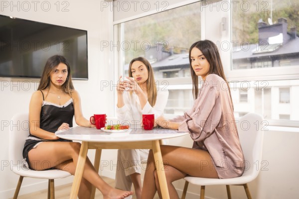 Lifestyle of Caucasian friends on vacation in a hotel having breakfast, dressed in nightwear,