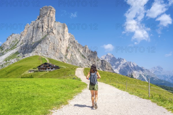 Female tourist walking on a gravel path enjoying the view of the nuvolau peak and the mountain