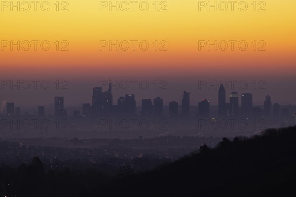 Shortly in front of sunrise, the sky behind the Frankfurt banking skyline turns yellow and orange,