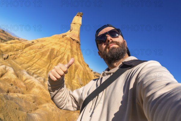 Tourist making thumbs up sign enjoying the view of the geological formations in bardenas reales