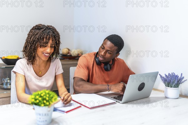 Young black entrepreneurs working from home using laptop and taking notes, collaborating on a