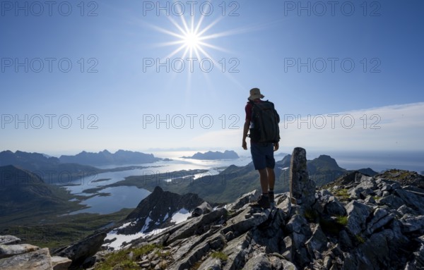 View of mountains and fjord landscape, mountaineer at the summit of Rundfjellet, Sun Star,
