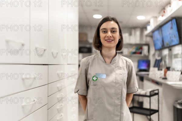 Young and proud female pharmacist standing with arms in the back in the storage room in a modern
