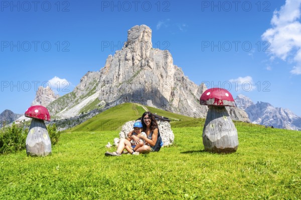 Mother and child are resting near wooden mushrooms at giau pass, a high mountain pass in the