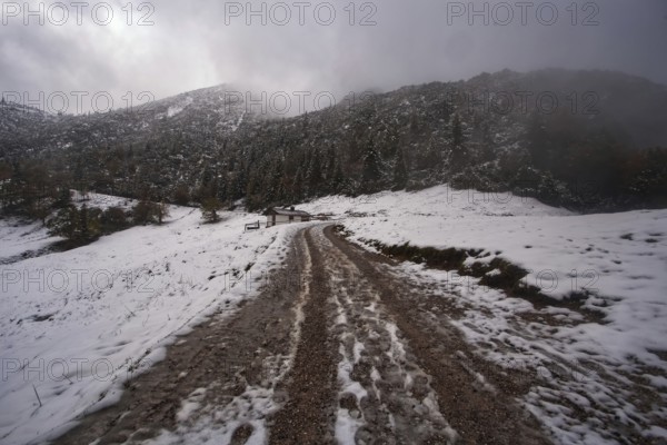 Snowy mountain landscape with cloudy sky and a narrow hiking trail to the Herzogstand, Kochel am