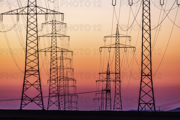 High-voltage pylons, overhead power lines at sunset. Schwieberdingen, Baden-Württemberg, Germany,