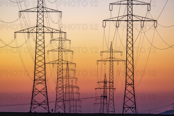 High-voltage pylons, overhead power lines at sunset. Schwieberdingen, Baden-Württemberg, Germany,