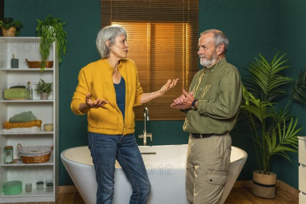 Casual caucasian senior couple discussing and talking standing together in the bathroom