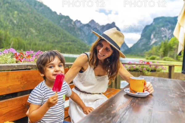 Mother and son enjoying a lakeside snack with a picturesque mountain backdrop in the dolomites