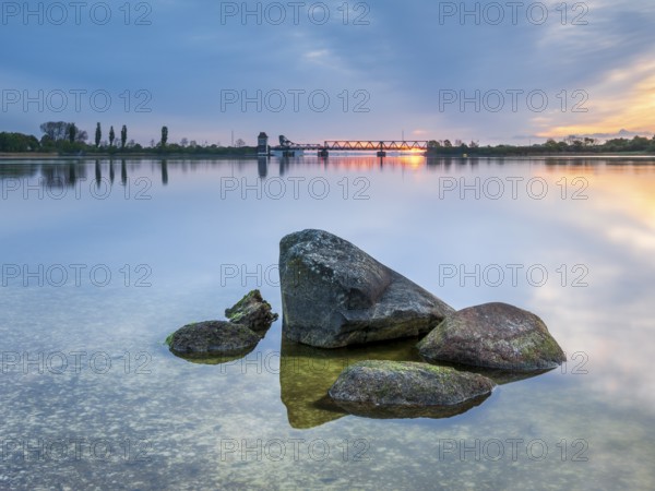 Sunrise at the historic lift bridge of Lindaunis over the Schlei, boulders in the water, Holstein