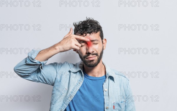 Young man with pain touching nose. A person with nasal bridge pain, Man with nasal bridge headache.