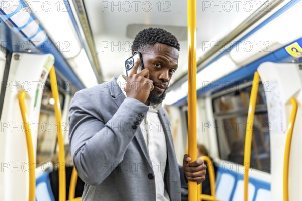 Young businessman commuting on public transport, using smartphone to stay connected while