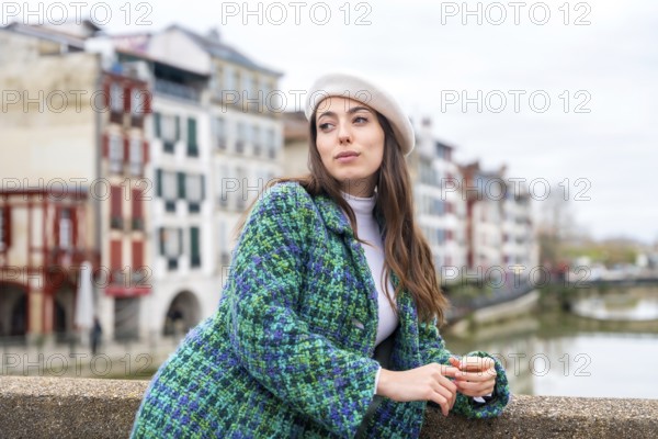 Cute woman in beret standing next to the river while visiting the city