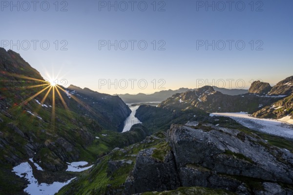 Picturesque mountain landscape at sunrise with sun star, fjord Trollfjord and Raftsund, hike to