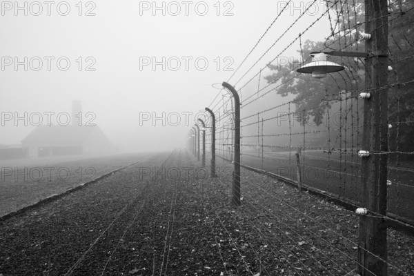 Reconstructed camp fence with crematorium in the fog at beech forest concentration camp, now a