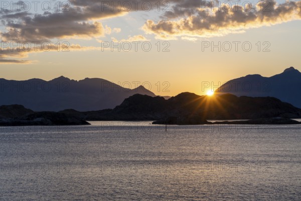 Sun setting behind Bergen, coastal landscape at sunset, Henningsvær, Lofoten, Nordland, Norway,