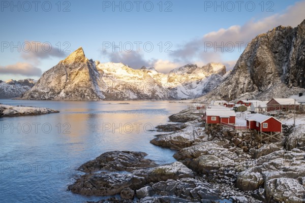 Rorbuer fishing huts in front of snow-covered mountains in winter, Hamnøy, Moskenesøy, Lofoten,