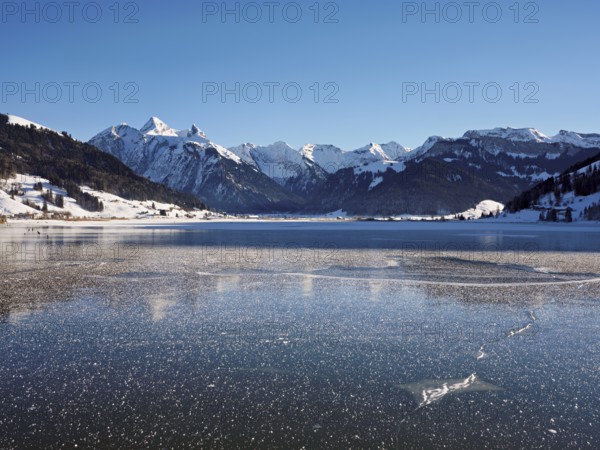 Frozen Sihlsee, reservoir, behind the snow-covered mountains Flübrig and Druesberg, Euthal, Canton