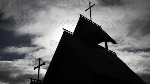 The silhouette of a church with several crosses against a cloudy sky, backdrop Kristin