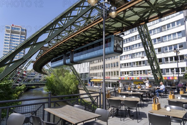 Train of the Wuppertal suspension railway runs along the Wupper, at the main station stop, terrace