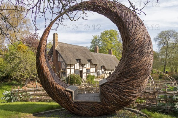 Anne Hathaway's Cottage framed by a round wicker seat, Shottery, Stratford-upon-Avon, Warwickshire,