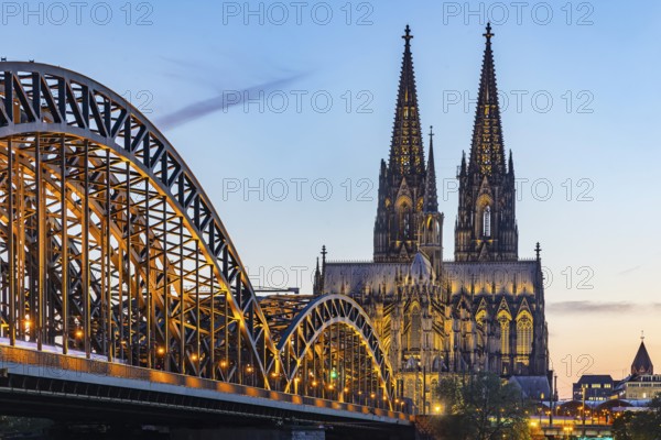 Cologne Cathedral, illuminated in the evening. Hohenzollern Bridge, railway bridge over the Rhine.