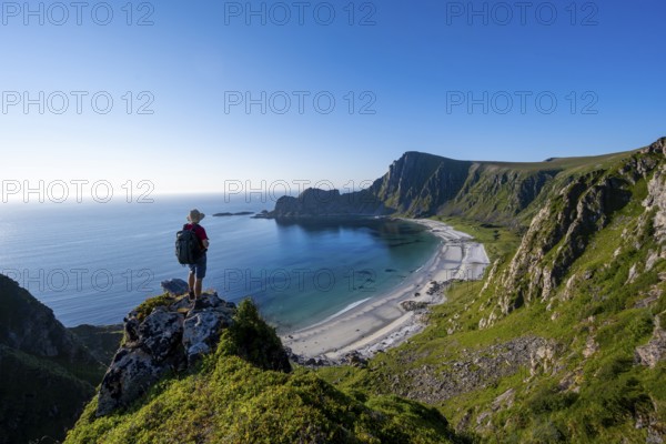 Mountaineer with view of coastal landscape, cliffs with summit Måtind or Måtinden, Høyvika beach