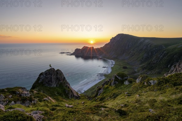 Climber on rocks in front of picturesque landscape, view of coastal landscape at sunset, cliffs and