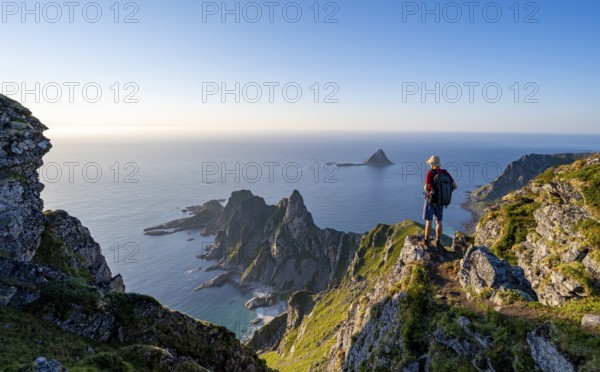 Mountaineer on the summit of Måtind or Måtinden, view of picturesque coastal landscape, rocky coast