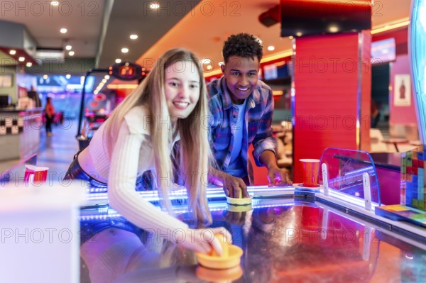 Two young friends enjoying a game of air hockey in a vibrant entertainment center, showcasing