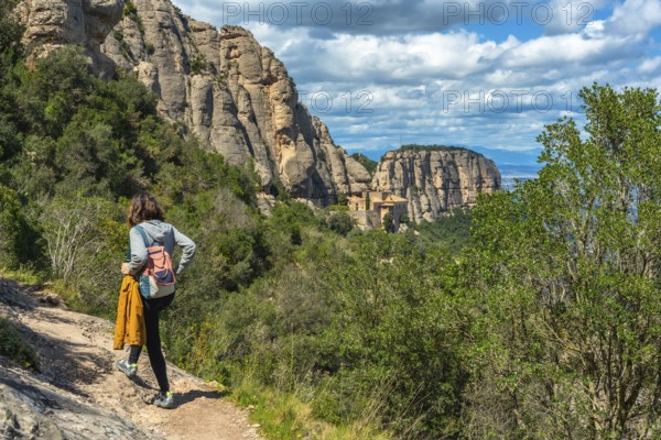 Female tourist walking on a hiking trail in montserrat mountains near barcelona with the santa