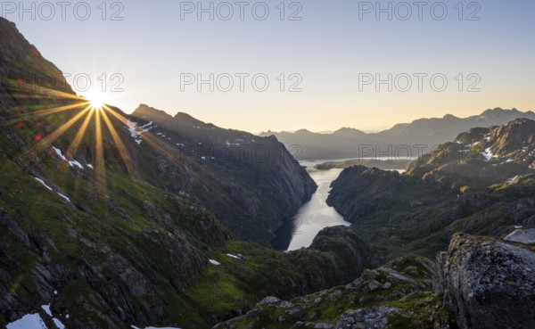 Picturesque mountain landscape at sunrise with sun star, fjord Trollfjord and Raftsund, hike to