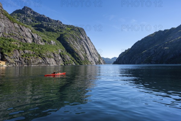 Kayaker with red kayak in the fjord Trollfjord, mountain peaks reflected in the water, fjord