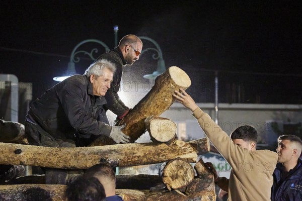Men working together at night to build a large pile of wood for a fire, Easter fire Psinthos, Holy