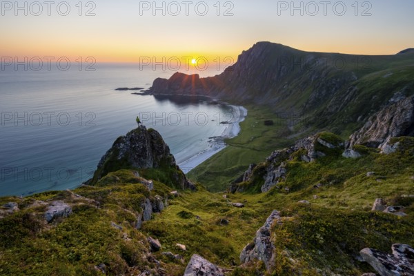 Climber on rocks in front of picturesque landscape, view of coastal landscape at sunset, cliffs and