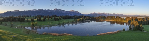 Panoramic view of a lake with mountains and forests at dawn, Hergratsrieder See, Alps, near Füssen,