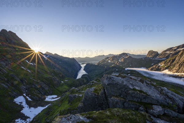 Picturesque mountain landscape at sunrise with sun star, fjord Trollfjord and Raftsund, hike to
