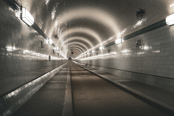 Symmetrically illuminated tiled tunnel with curved lines and depth, old Elbe tunnel, Hamburg,
