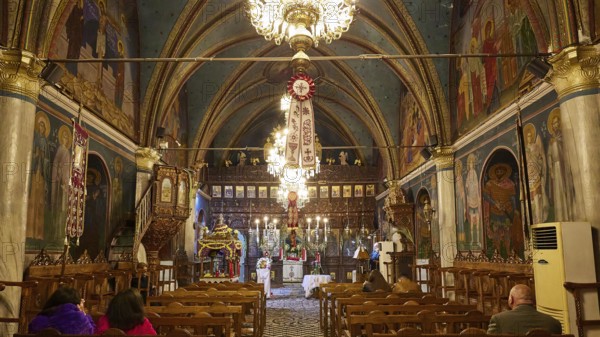 Interior of a church with paintings and chandeliers, people sitting in the pews, Easter fire