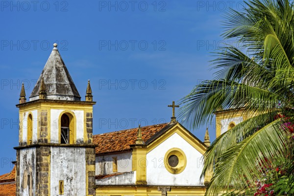 Beautiful baroque church tower amidst the vegetation of the city of Olinda with the sea in the