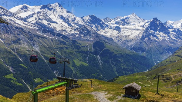Gondolas of the cable car from Zinal to Corne de Sorebois, behind the snow-covered peaks Weisshorn,