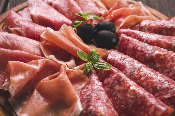 Assortment, sliced meat appetizer, prosciutto, salami and ham, with olives, breakfast, top view,