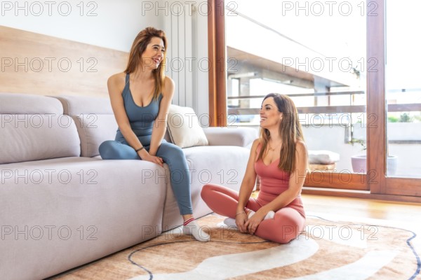 Two friends practicing yoga and meditation in a bright living room, enjoying an online class