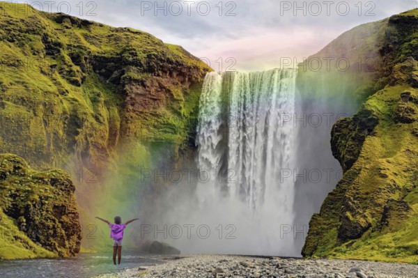 Child in front of Skogar waterfall rainbow Iceland