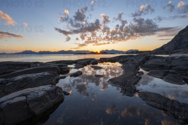 Clouds reflected in a small pond on a rocky coast, coastal landscape at sunset, Henningsvær,