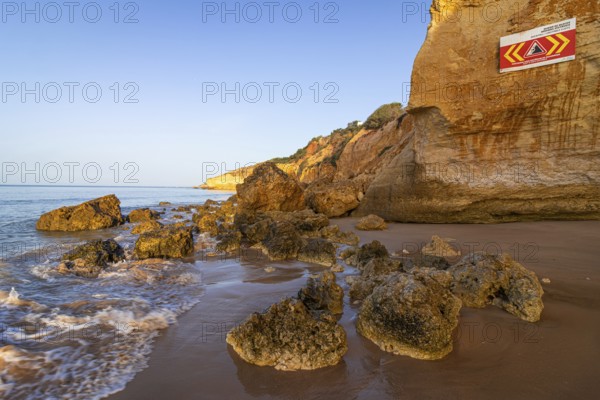 ROCKFALL UNSTABLE CLIFFS, KEEP A SAFE DISTANCE is written in English on a warning sign in Portugal