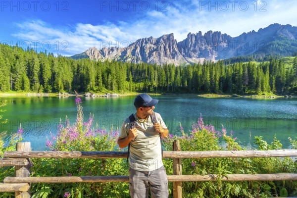 Hiker admiring the stunning scenery of lake carezza with the latemar mountain range in the