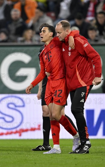 Jamal Musiala FC Bayern Munich FCB (42) injured Injury is escorted off the pitch by the attendants
